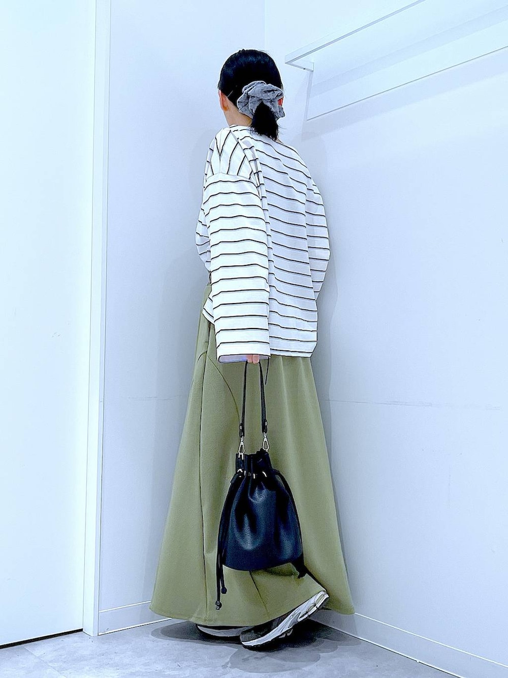 ブラック系のショルダーバッグ、グリーン系のスカート、ホワイト系のTシャツ/カットソーを着用したレディースの冬コーディネートの3枚目の写真