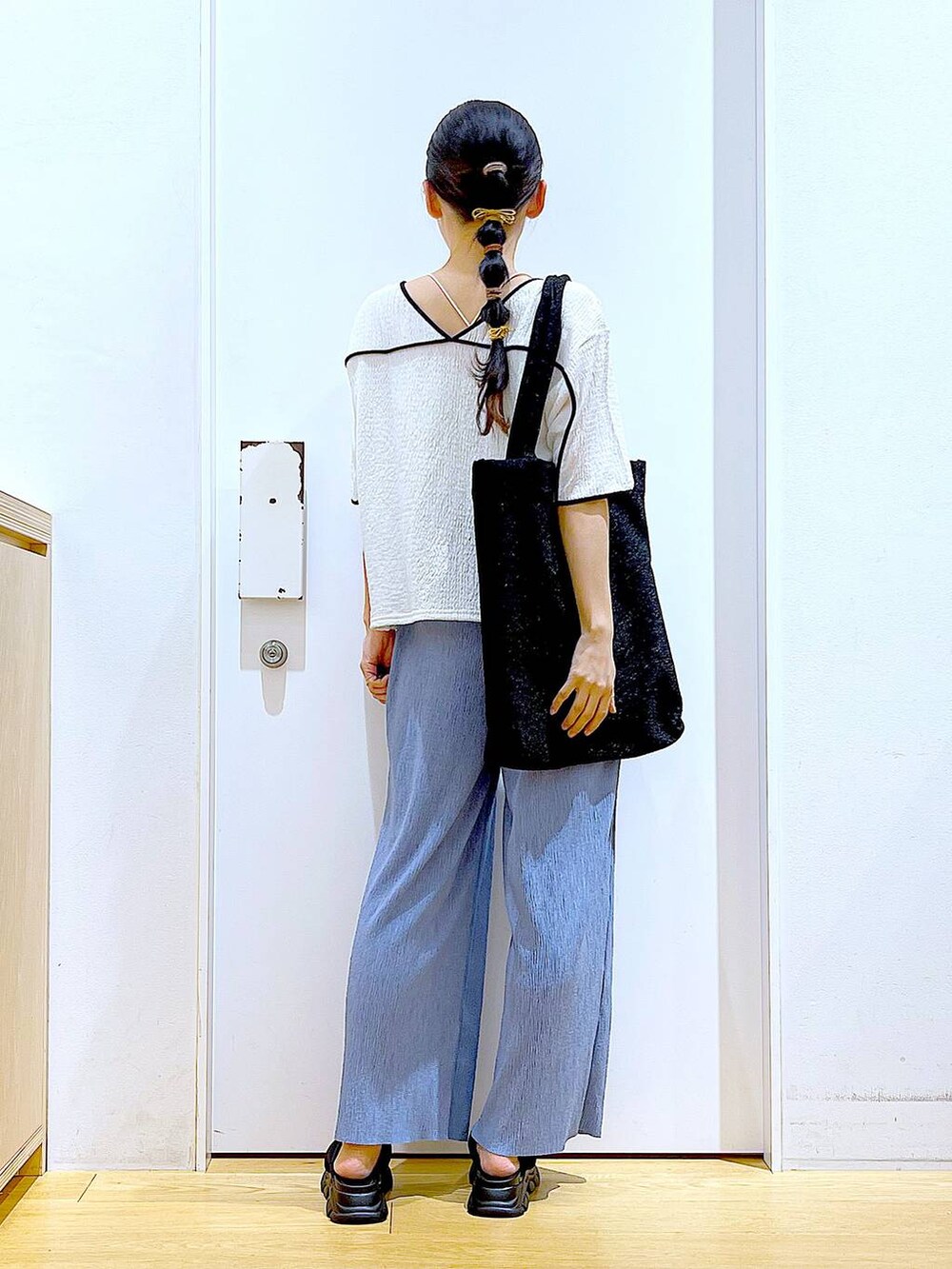 ブラック系のトートバッグ、ブラック系のサンダル、ホワイト系のTシャツ/カットソーを着用したレディースの夏コーディネートの5枚目の写真