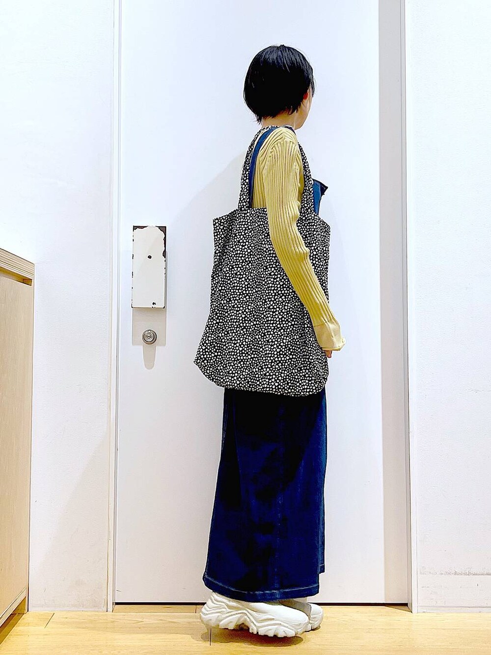 ブルー系のジャンパースカート、ブラック系のトートバッグ、イエロー系のニット/セーターを着用したレディースの秋コーディネートの4枚目の写真