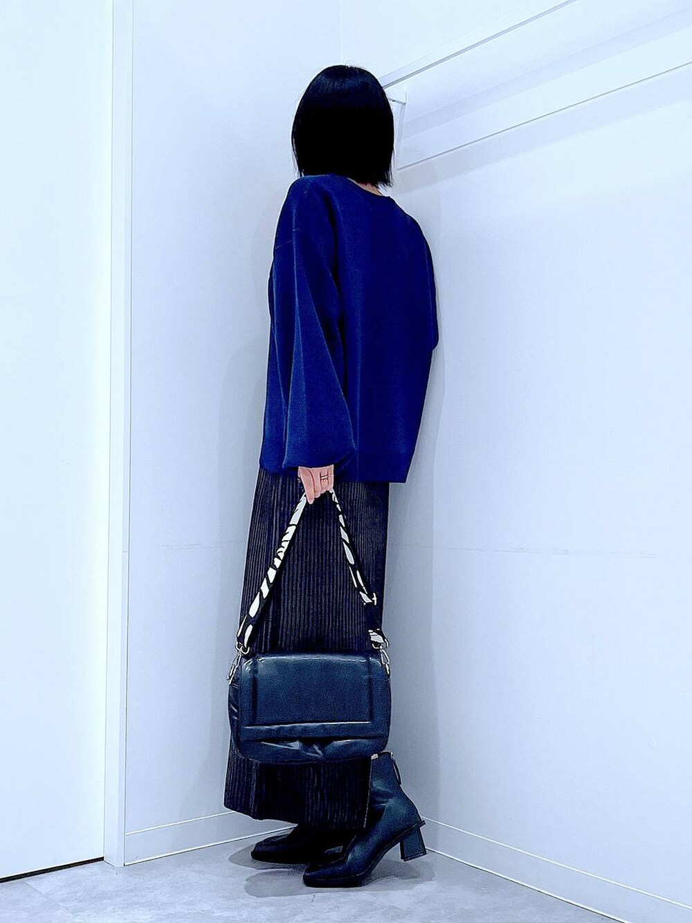 ブラック系のスカート、ブラック系のショルダーバッグ、ブラック系のブーツを着用したレディースの冬コーディネートの3枚目の写真