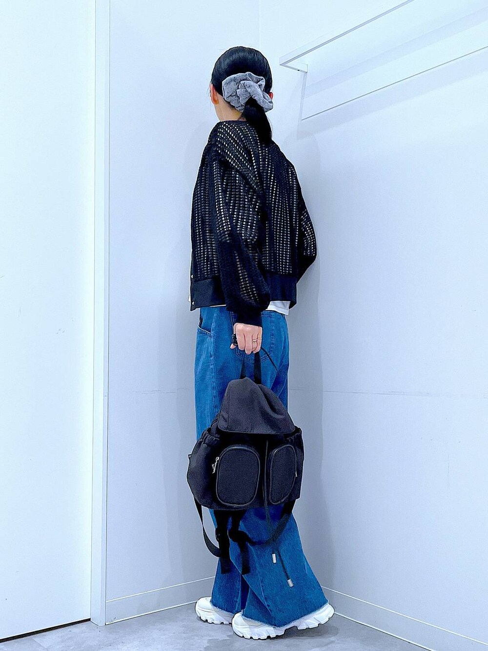 ブラック系のバックパック/リュック、ホワイト系のスニーカー、ブルー系のデニムパンツを着用したレディースの春コーディネートの3枚目の写真