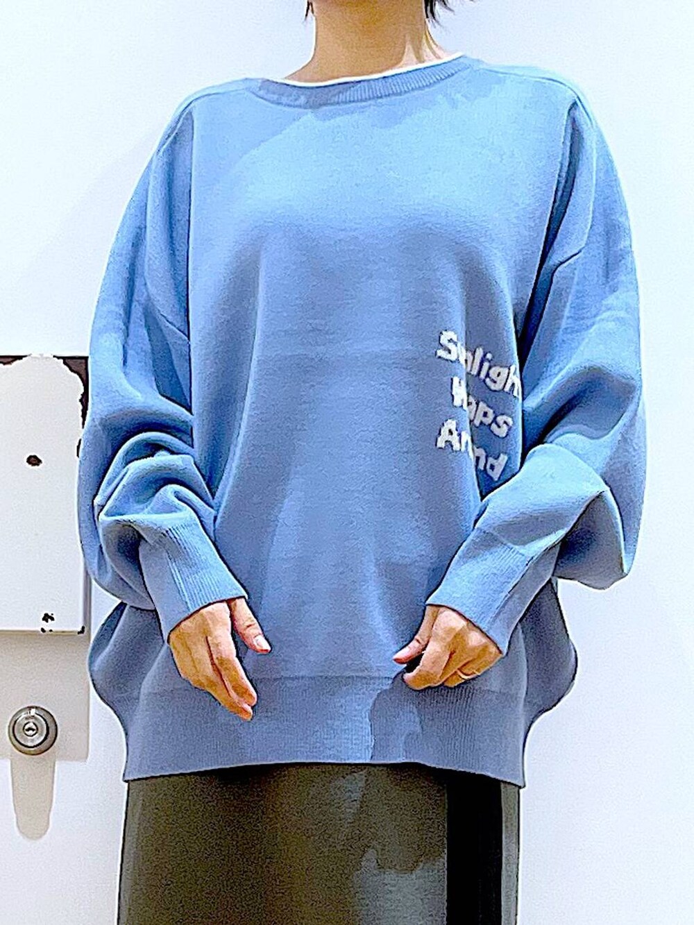 ブルー系のニット/セーター、ブラック系のショルダーバッグ、グレー系のスカートを着用したレディースの冬コーディネートの7枚目の写真