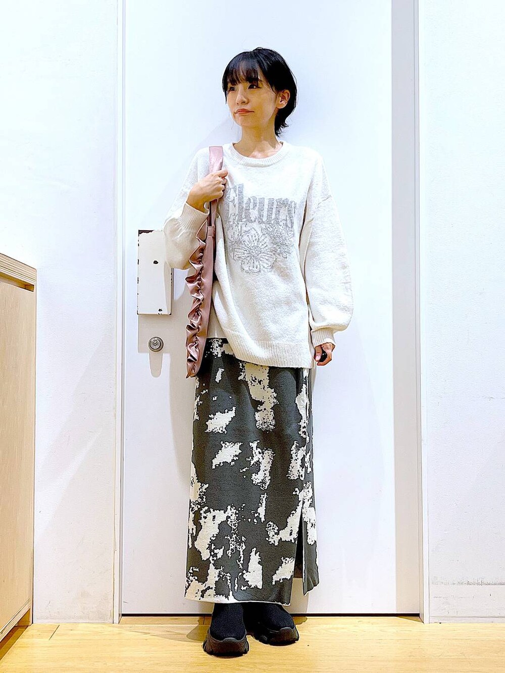 グレー系のスカート、ブラック系のブーツ、ベージュ系のニット/セーターを着用したレディースの秋コーディネートの2枚目の写真