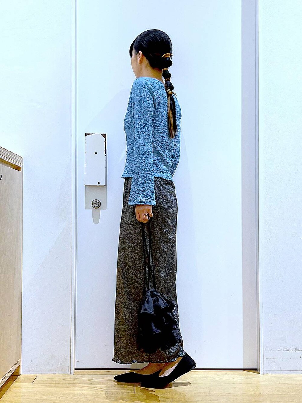 ブラック系のスカート、ブラック系のショルダーバッグ、ブラック系のパンプスを着用したレディースの春コーディネートの3枚目の写真