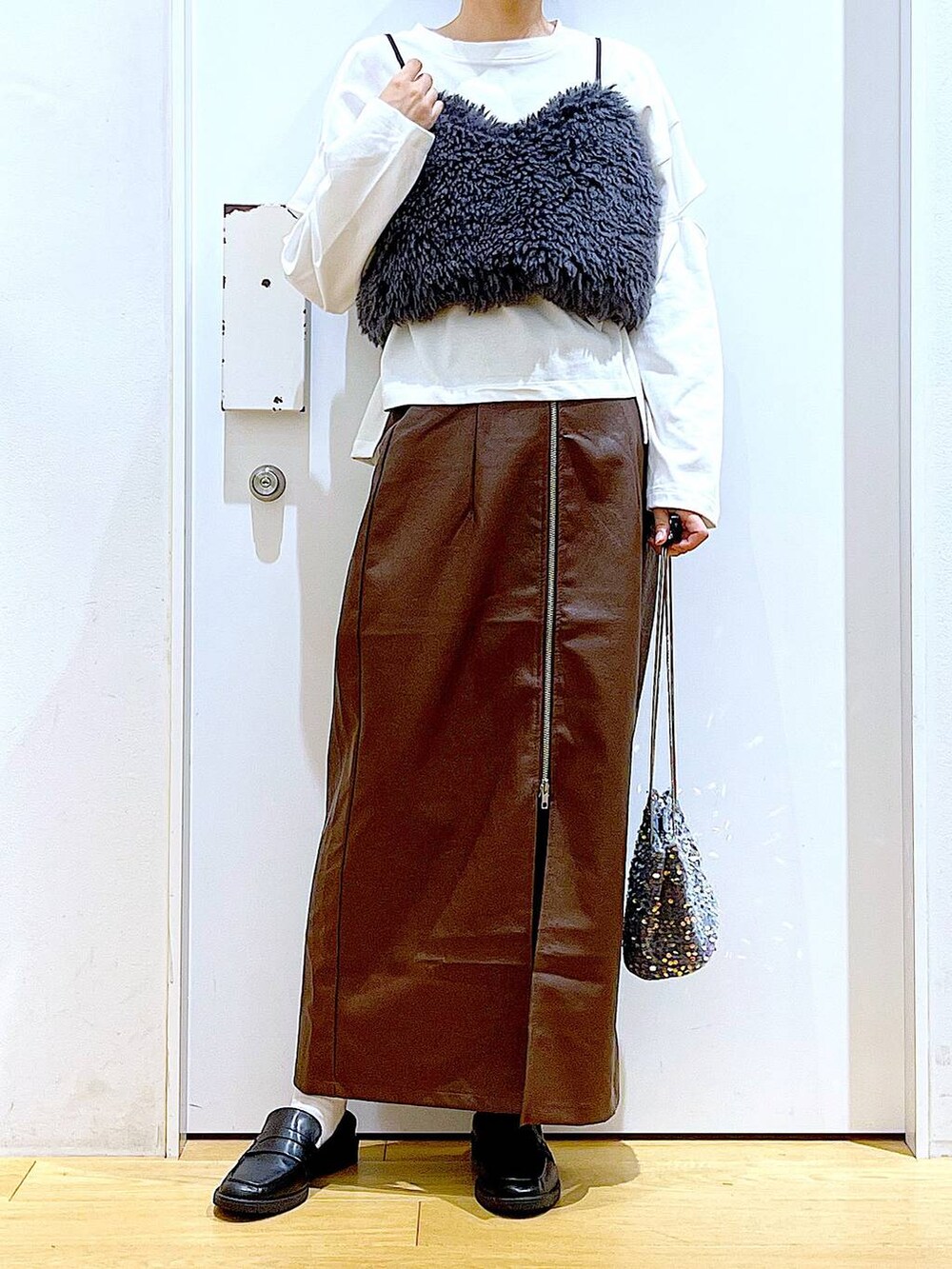 ブラウン系のスカート、グレー系のベスト、ブラック系のローファーを着用したレディースの秋コーディネートの6枚目の写真