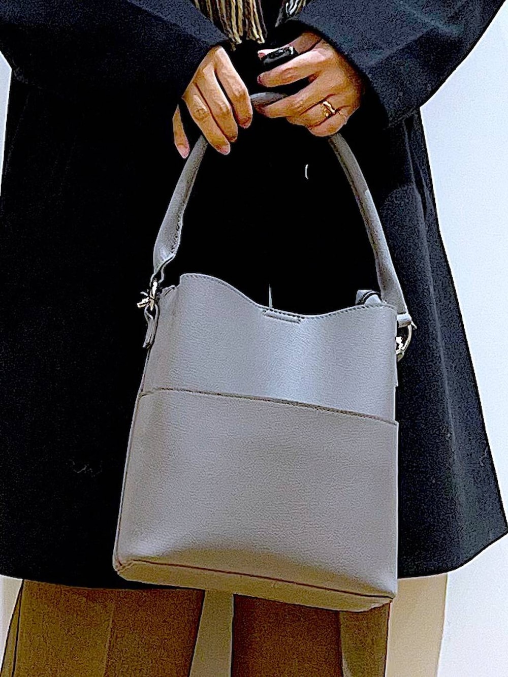 ブラック系のノーカラーコート、グレー系のショルダーバッグ、グレー系のニット/セーターを着用したレディースの冬コーディネートの7枚目の写真