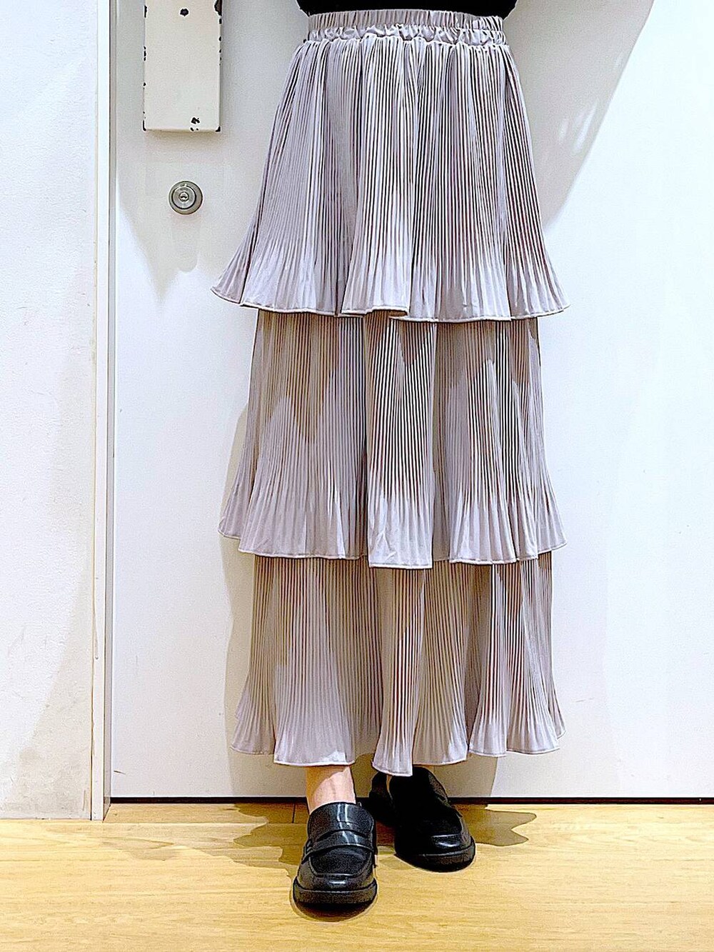 グレー系のスカート、ブラック系のトートバッグ、ブラック系のローファーを着用したレディースの秋コーディネートの8枚目の写真