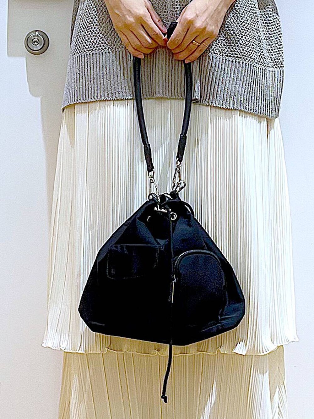 ブラック系のパンプス、ホワイト系のスカート、グレー系のニット/セーターを着用したレディースの春コーディネートの9枚目の写真