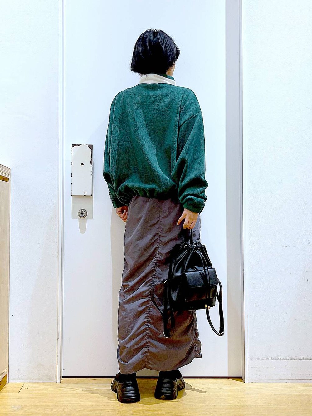 ブラック系のバックパック/リュック、グレー系のスカート、ブラック系のブーツを着用したレディースの冬コーディネートの5枚目の写真