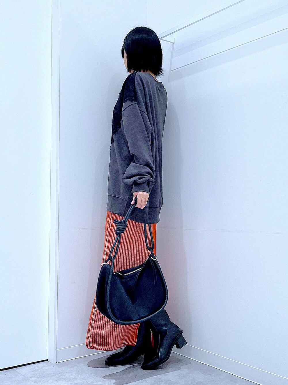 オレンジ系のスカート、ブラック系のブーツ、ブラック系のショルダーバッグを着用したレディースの秋コーディネートの3枚目の写真