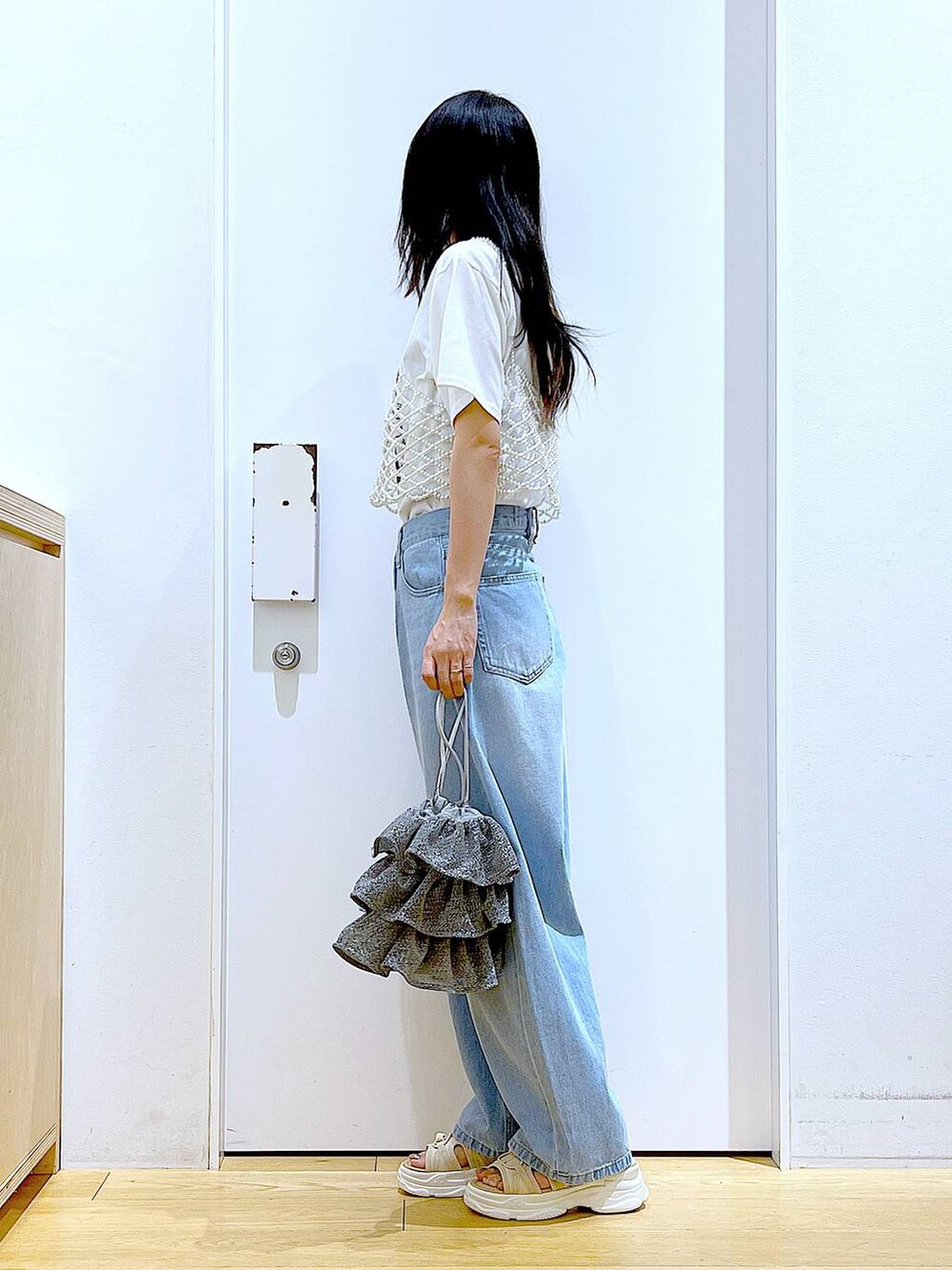 シルバー系のショルダーバッグ、ベージュ系のサンダル、ブルー系のデニムパンツを着用したレディースの夏コーディネートの3枚目の写真