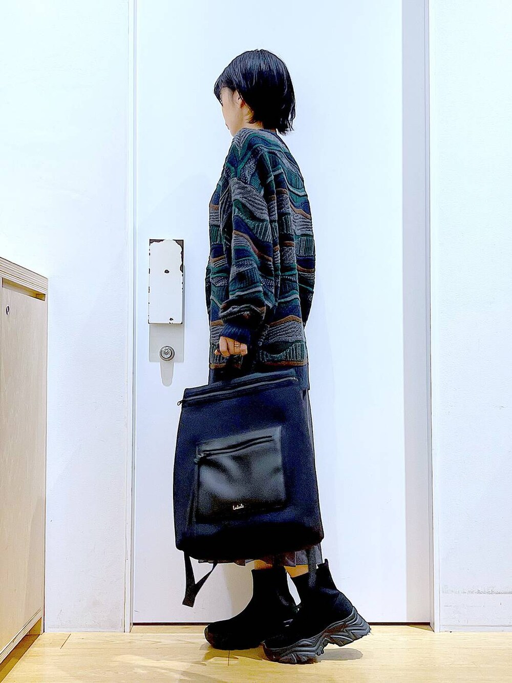 ブラック系のバックパック/リュック、ブラック系のブーツ、グレー系のスカートを着用したレディースの秋コーディネートの3枚目の写真