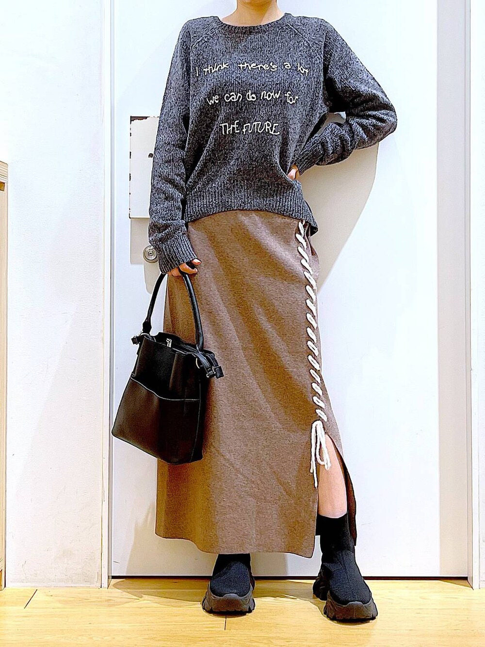 ブラック系のブーツ、ブラック系のショルダーバッグ、ブラウン系のスカートを着用したレディースの冬コーディネートの6枚目の写真