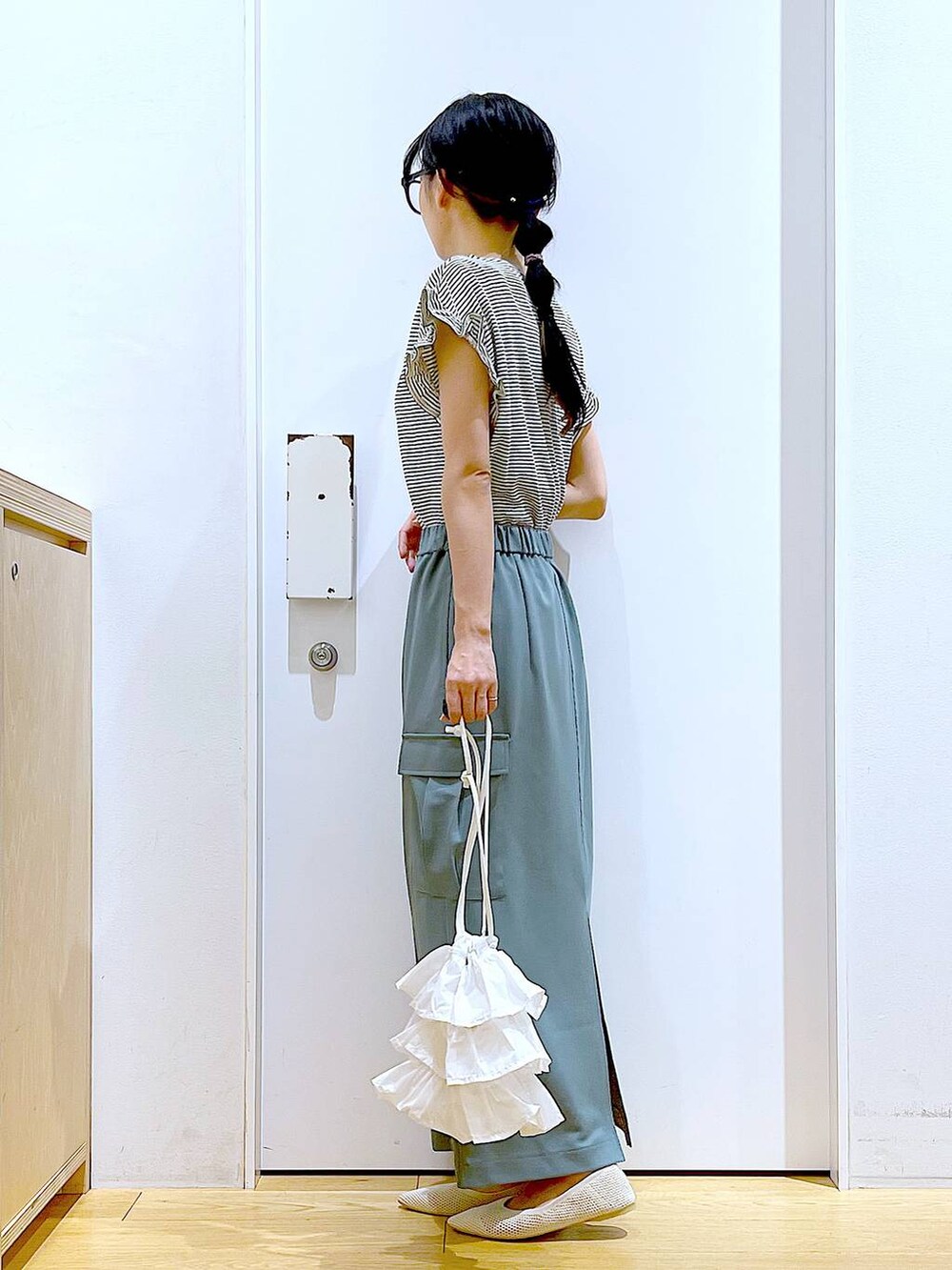 ホワイト系のショルダーバッグ、ホワイト系のパンプス、グリーン系のスカートを着用したレディースの春コーディネートの3枚目の写真