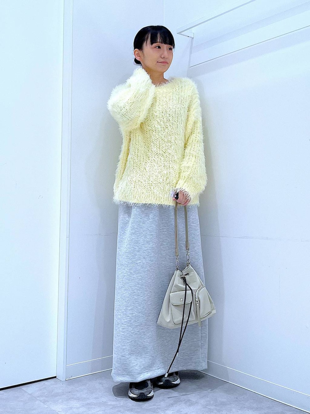 イエロー系のニット/セーター、グレー系のスカート、パープル系のバレッタ/ヘアクリップを着用したレディースの冬コーディネートの2枚目の写真