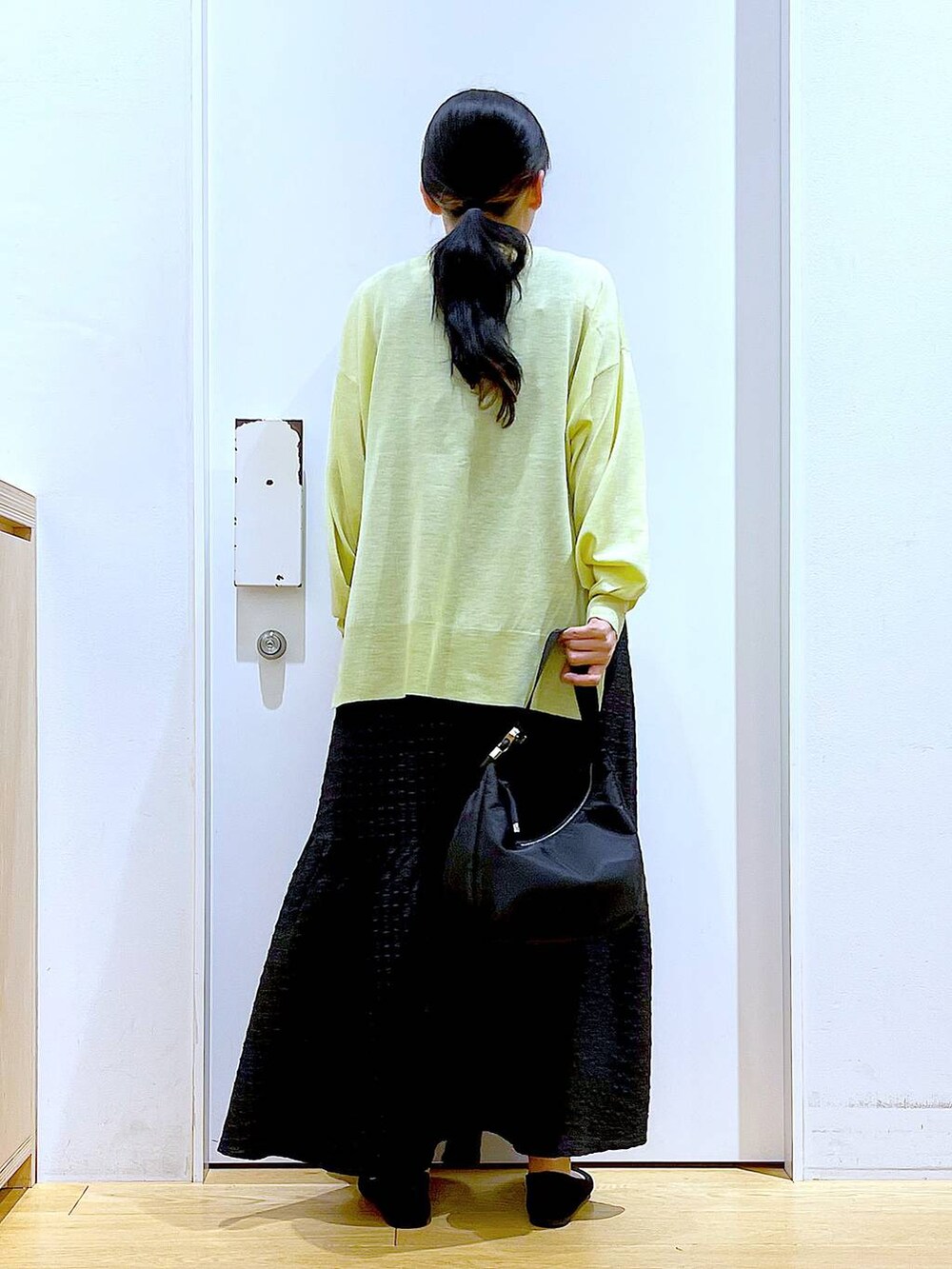 ブラック系のワンピース、グリーン系のカーディガン/ボレロ、ブラック系のショルダーバッグを着用したレディースの春コーディネートの5枚目の写真