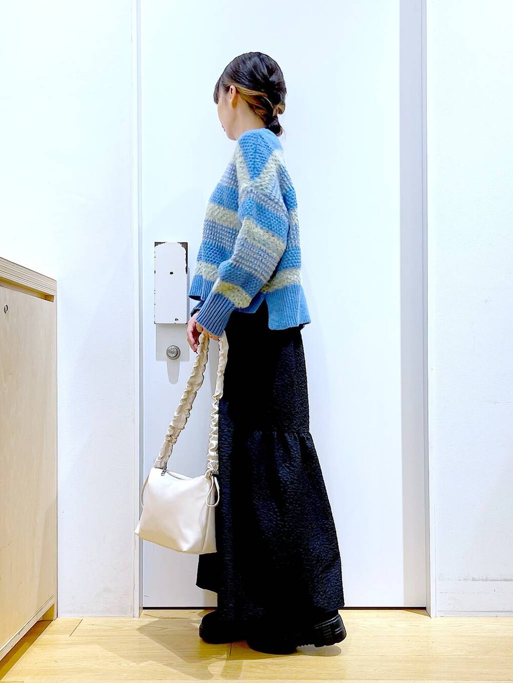 ホワイト系のショルダーバッグ、ブラック系のブーツ、ブラック系のスカートを着用したレディースの冬コーディネートの3枚目の写真