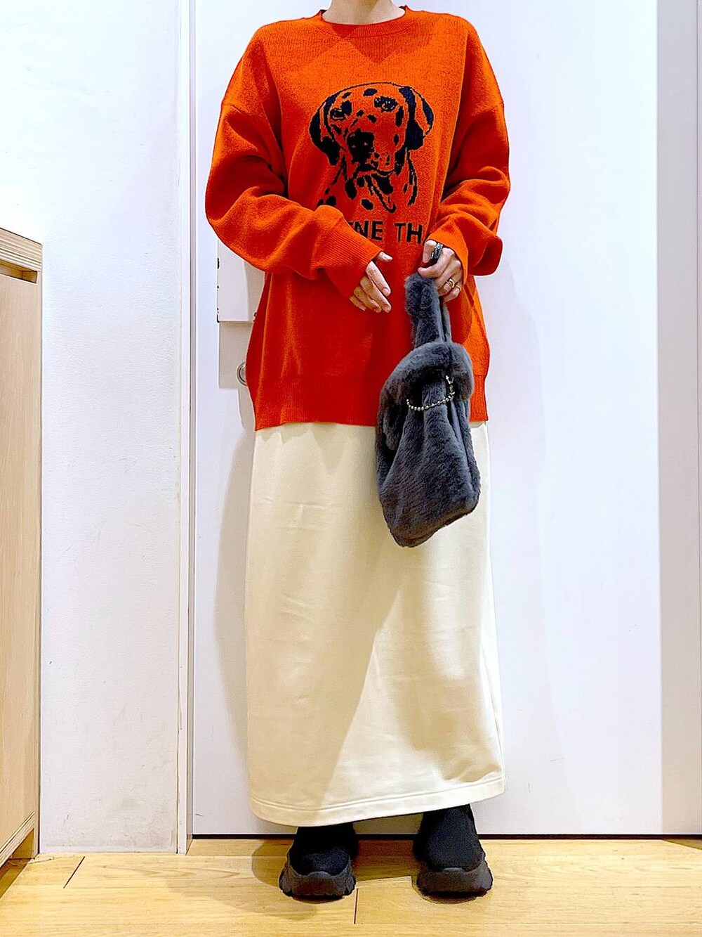 グレー系のショルダーバッグ、オレンジ系のニット/セーター、ブラック系のブーツを着用したレディースの冬コーディネートの6枚目の写真