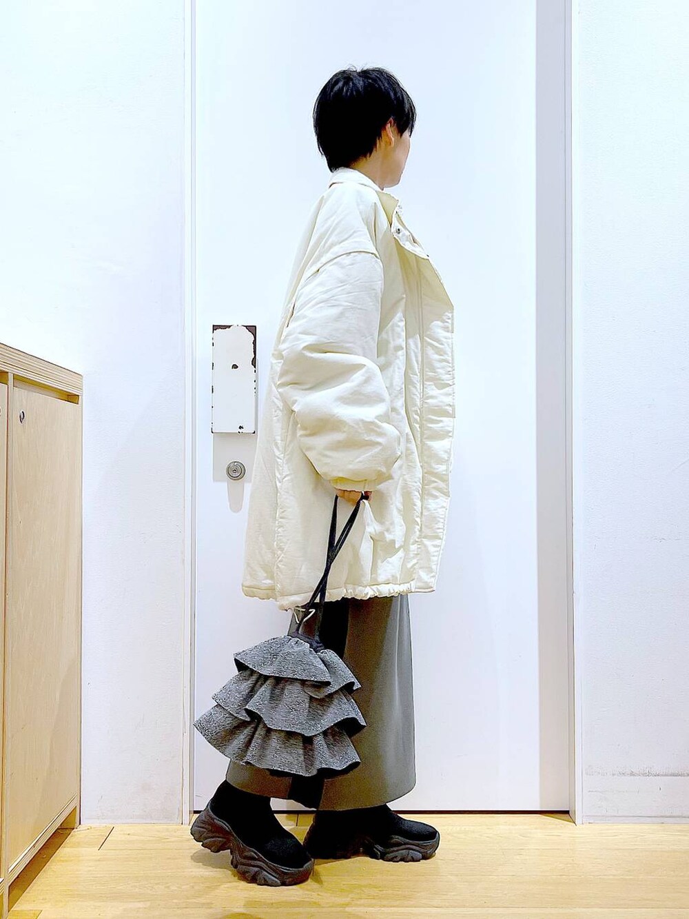 グレー系のスカート、ブラック系のブーツ、ホワイト系のその他アウターを着用したレディースの冬コーディネートの4枚目の写真