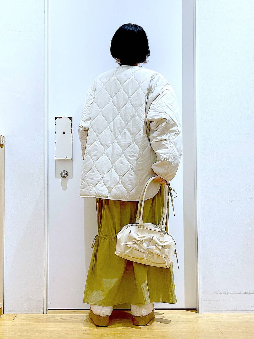 ベージュ系のブルゾン、ベージュ系のスリッポン、ホワイト系のハンドバッグを着用したレディースの秋コーディネートの5枚目の写真