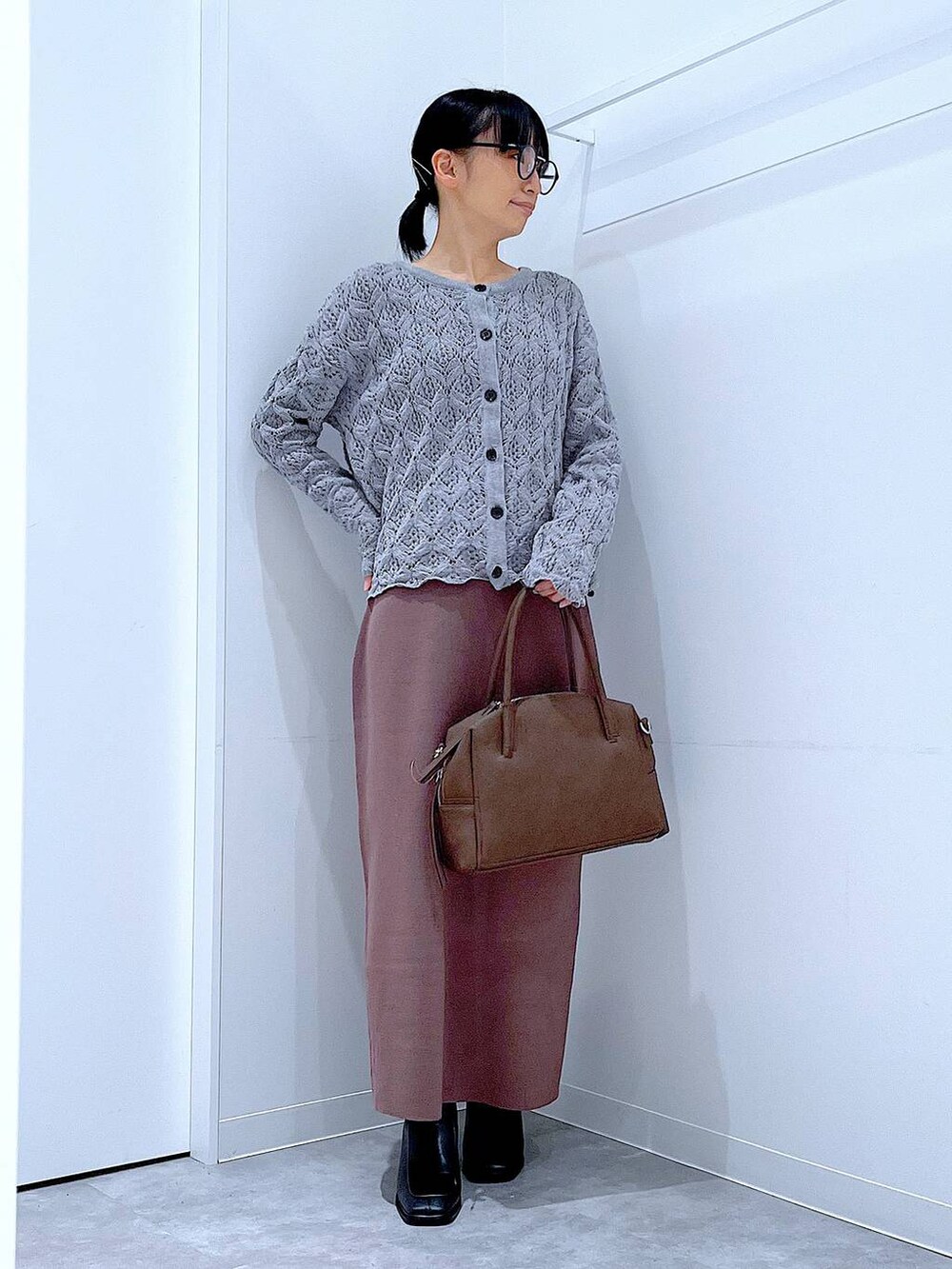ブラウン系のボストンバッグ、ブラック系のブーツ、グレー系のカーディガン/ボレロを着用したレディースの冬コーディネートの2枚目の写真