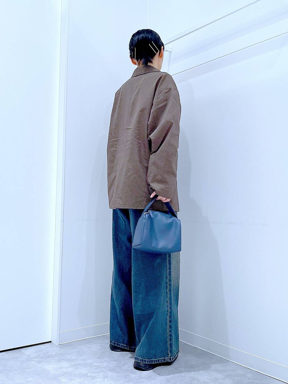 ブラック系のローファー、ブルー系のショルダーバッグ、ブルー系のデニムパンツを着用したレディースの秋コーディネートの4枚目の写真