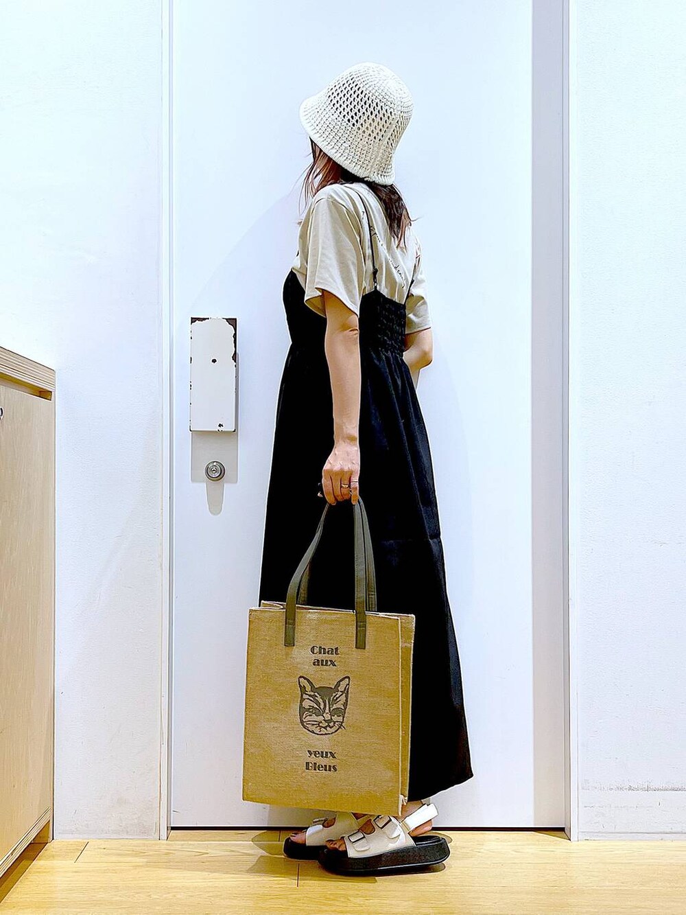 ホワイト系のサンダル、グレー系のトートバッグ、ブラック系のワンピースを着用したレディースの夏コーディネートの3枚目の写真