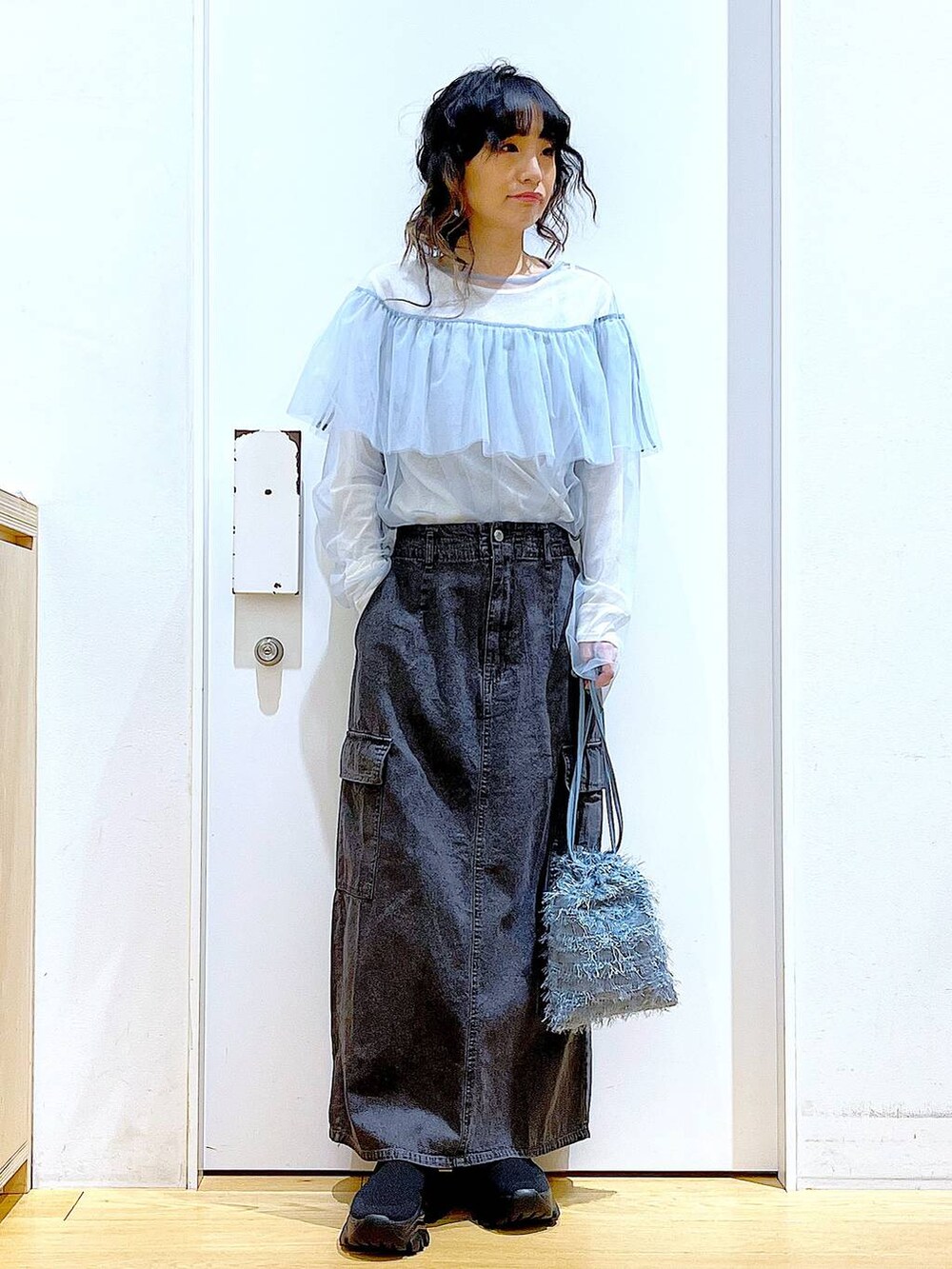 グレー系のデニムスカート、ブラック系のスニーカー、ブルー系のその他トップスを着用したレディースの春コーディネートの2枚目の写真