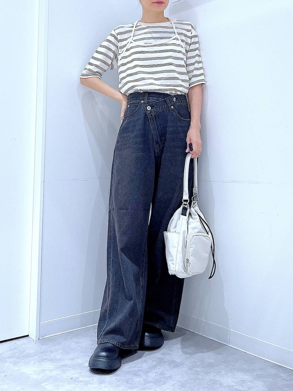ブラック系のデニムパンツ、ホワイト系のハンドバッグ、ベージュ系のTシャツ/カットソーを着用したレディースの秋コーディネートの6枚目の写真