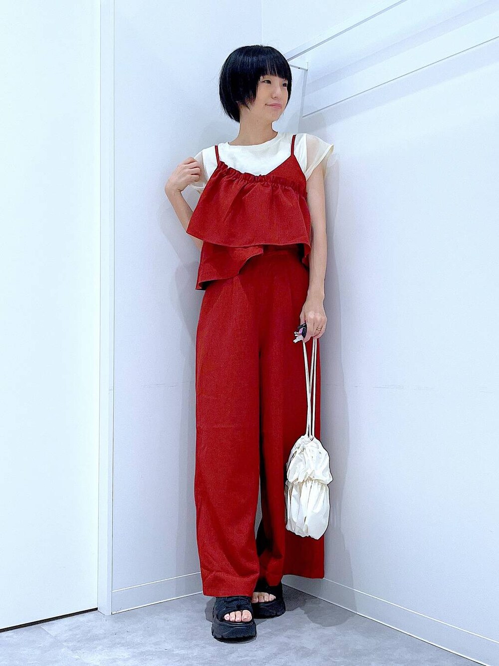 ブラック系のスニーカー、ホワイト系のショルダーバッグ、レッド系のつなぎ/オールインワンを着用したレディースの夏コーディネートの2枚目の写真