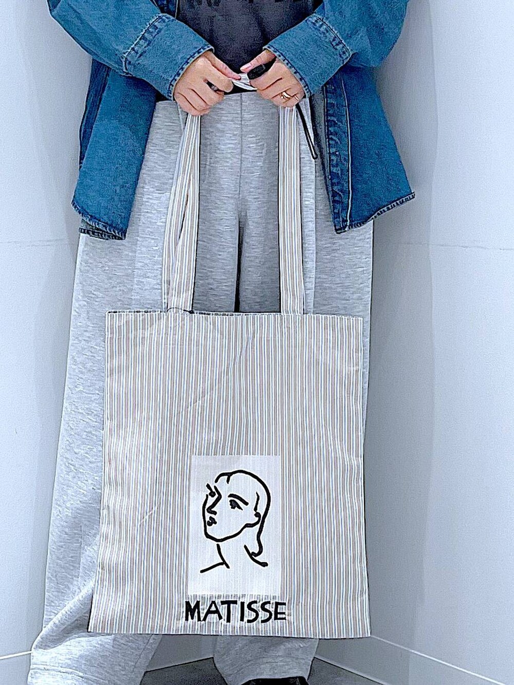 ブルー系のシャツ/ブラウス、ブラウン系のトートバッグ、グレー系のTシャツ/カットソーを着用したレディースの秋コーディネートの9枚目の写真