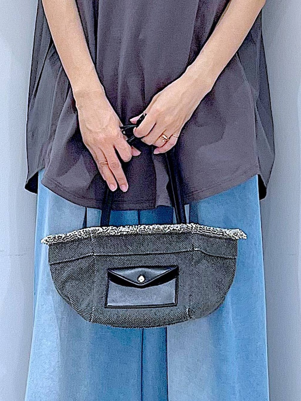 ブラック系のショルダーバッグ、ブラック系のサンダル、ブルー系のデニムパンツを着用したレディースの夏コーディネートの9枚目の写真