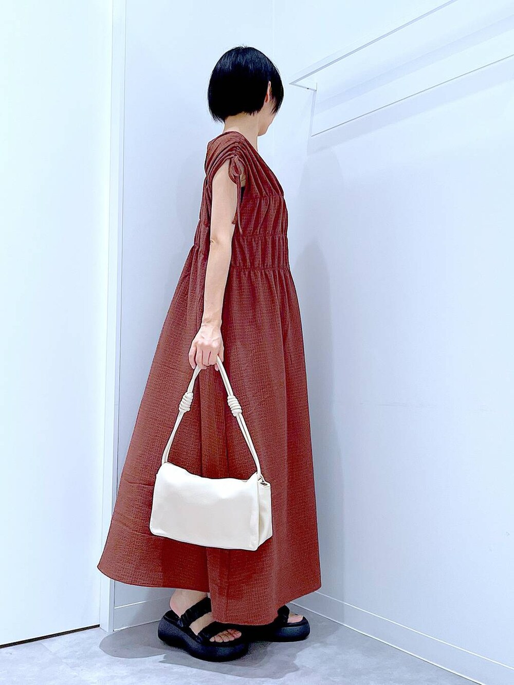 ブラック系のサンダル、ホワイト系のショルダーバッグ、ブラウン系のワンピースを着用したレディースの夏コーディネートの4枚目の写真