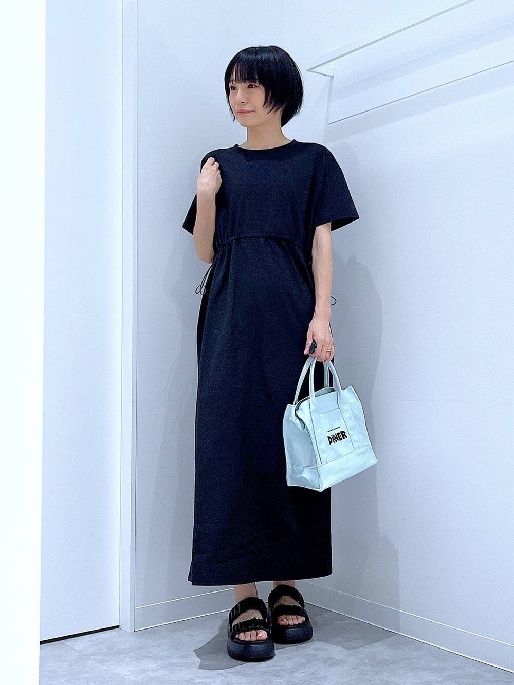 ブラック系のサンダル、ブラック系のワンピース、グリーン系のトートバッグを着用したレディースの夏コーディネートの2枚目の写真