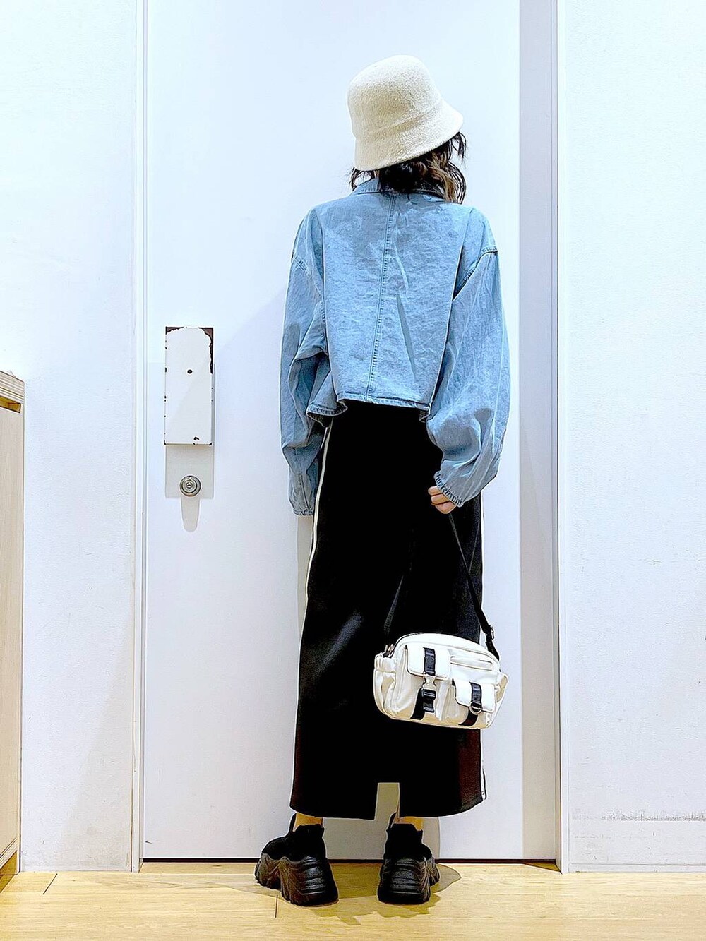 ブルー系のデニムジャケット、ブラック系のスカート、ブラック系のスニーカーを着用したレディースの春コーディネートの5枚目の写真