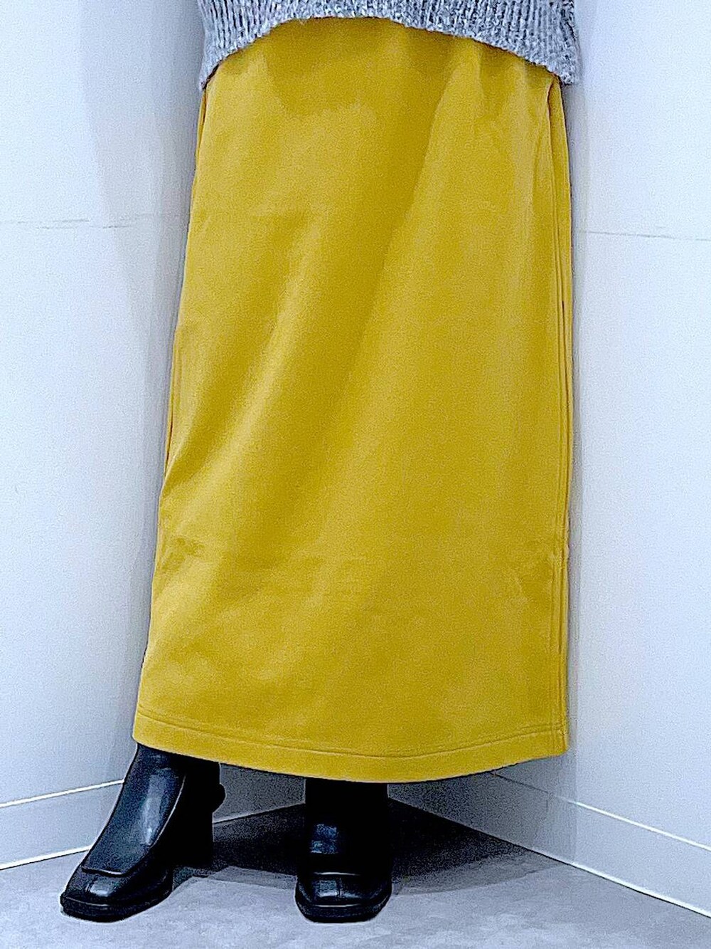 グレー系のニット/セーター、イエロー系のスカート、ブラック系のブーツを着用したレディースの冬コーディネートの8枚目の写真