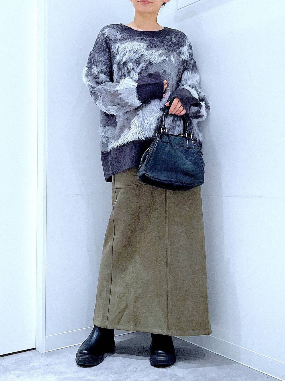 ブラック系のブーツ、ブラック系のニット/セーター、ブラック系のショルダーバッグを着用したレディースの冬コーディネートの6枚目の写真