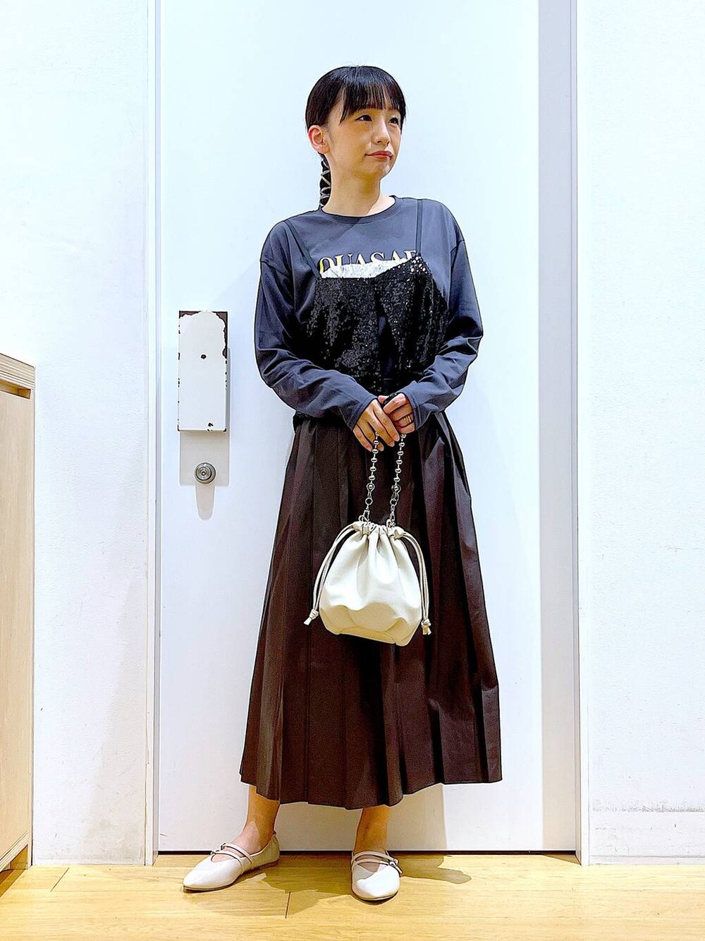 ベージュ系のショルダーバッグ、ホワイト系のパンプス、ブラック系のベストを着用したレディースの秋コーディネートの2枚目の写真