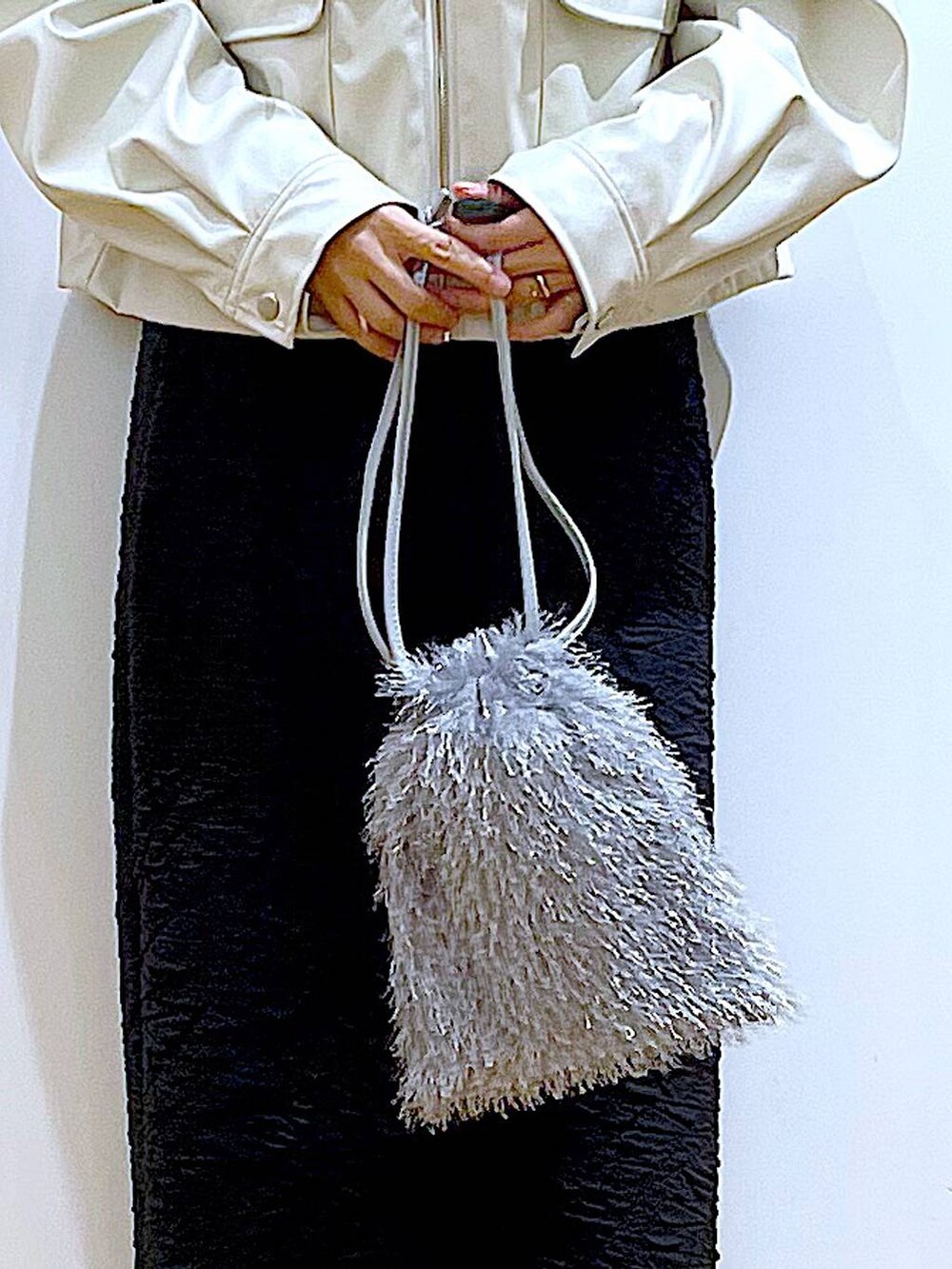 ブラック系のスカート、ベージュ系のブルゾン、ベージュ系のブーツを着用したレディースの春コーディネートの9枚目の写真