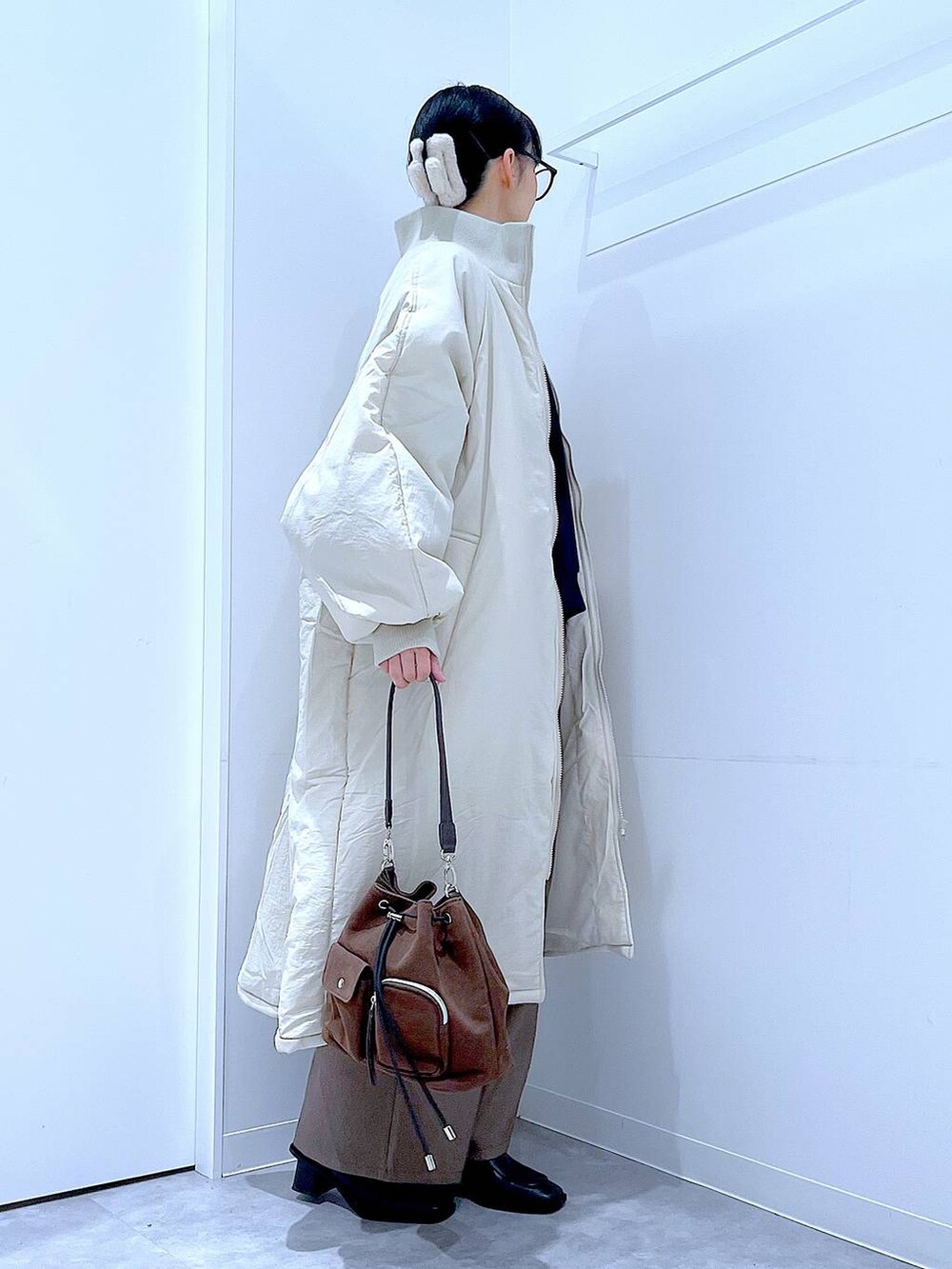 ホワイト系のブルゾン、ブラウン系のショルダーバッグ、ブラック系のブーツを着用したレディースの冬コーディネートの4枚目の写真