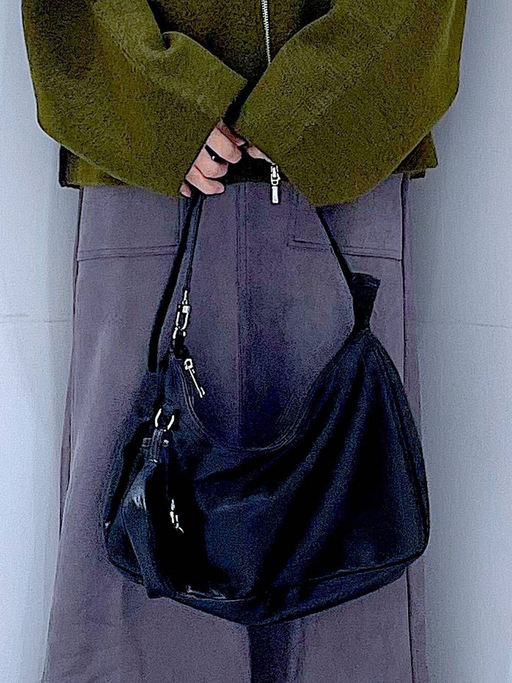 グリーン系のブルゾン、ブラック系のブーツ、ブラック系のショルダーバッグを着用したレディースの秋コーディネートの9枚目の写真