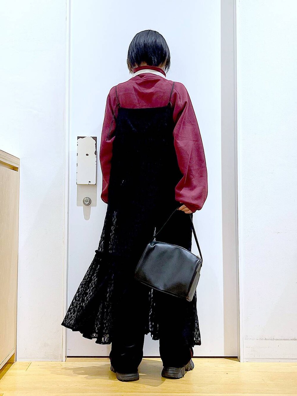 ブラック系のショルダーバッグ、ブラック系のワンピース、ブラック系のブーツを着用したレディースの冬コーディネートの5枚目の写真