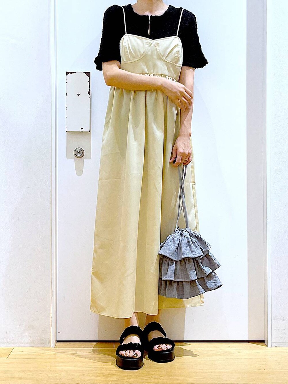 ブラック系のサンダル、イエロー系のワンピース、ブラック系のカーディガン/ボレロを着用したレディースの夏コーディネートの6枚目の写真