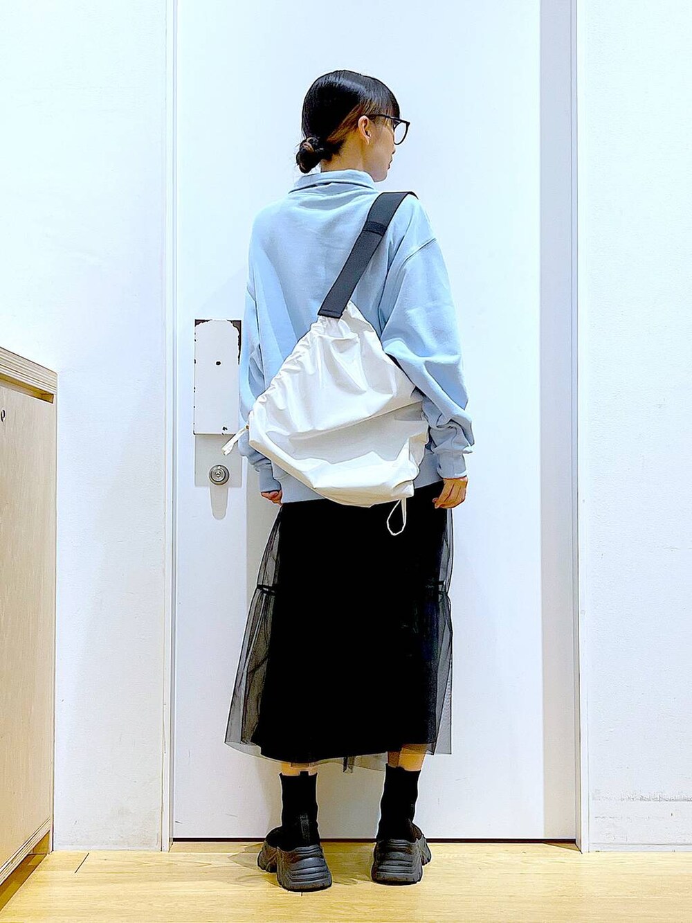 ブルー系のスウェット、ブラック系のブーツ、ホワイト系のショルダーバッグを着用したレディースの春コーディネートの5枚目の写真