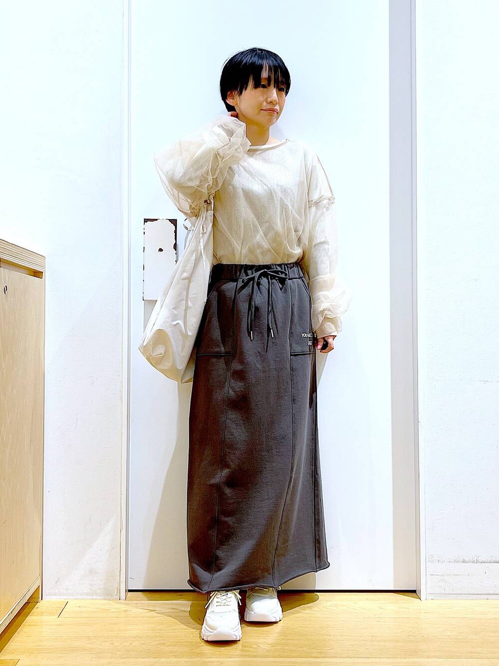 ホワイト系のショルダーバッグ、ホワイト系のスニーカー、グレー系のスカートを着用したレディースの春コーディネートの2枚目の写真