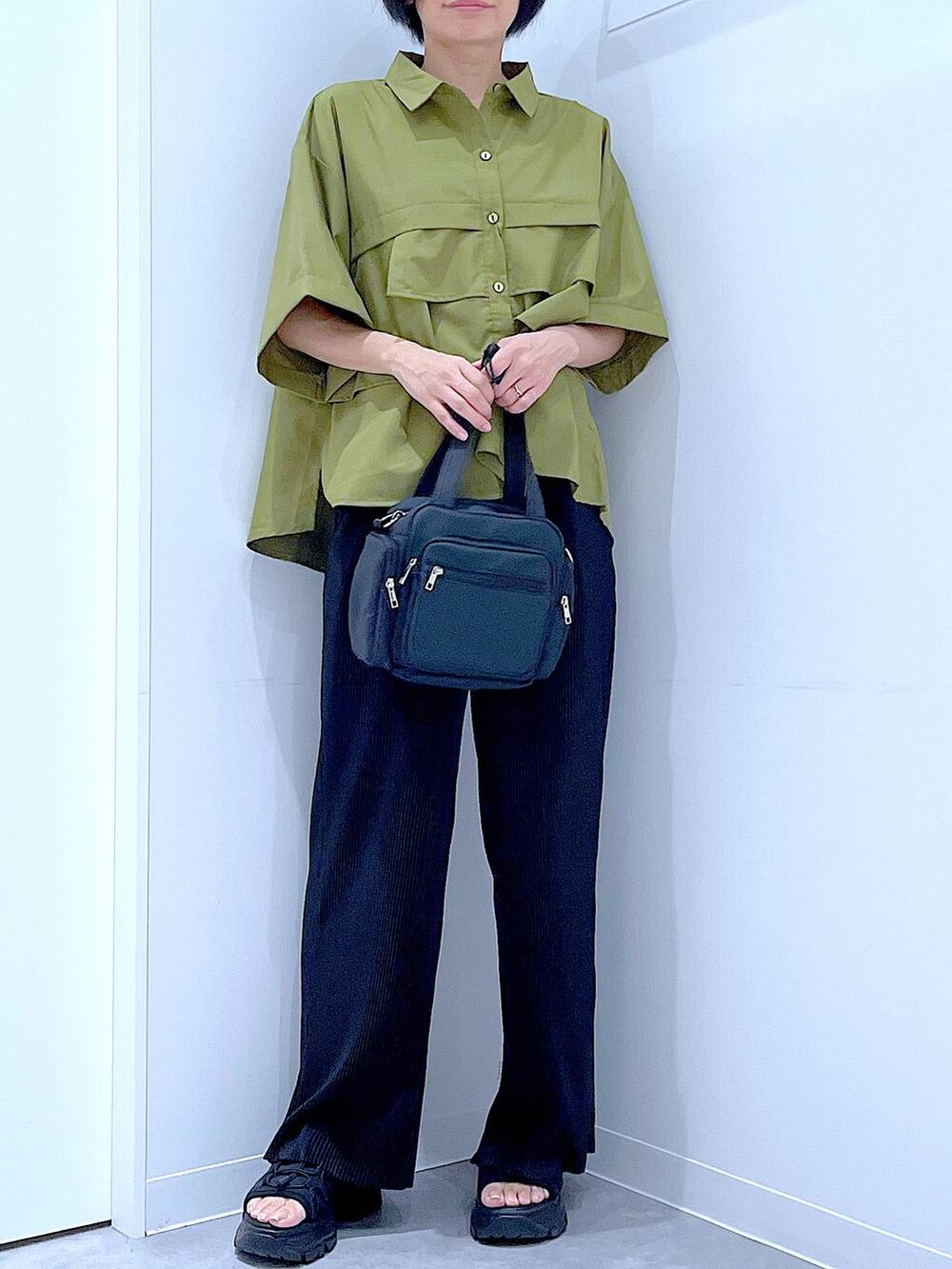 ブラック系のスニーカー、ブラック系のショルダーバッグ、グリーン系のシャツ/ブラウスを着用したレディースの夏コーディネートの6枚目の写真