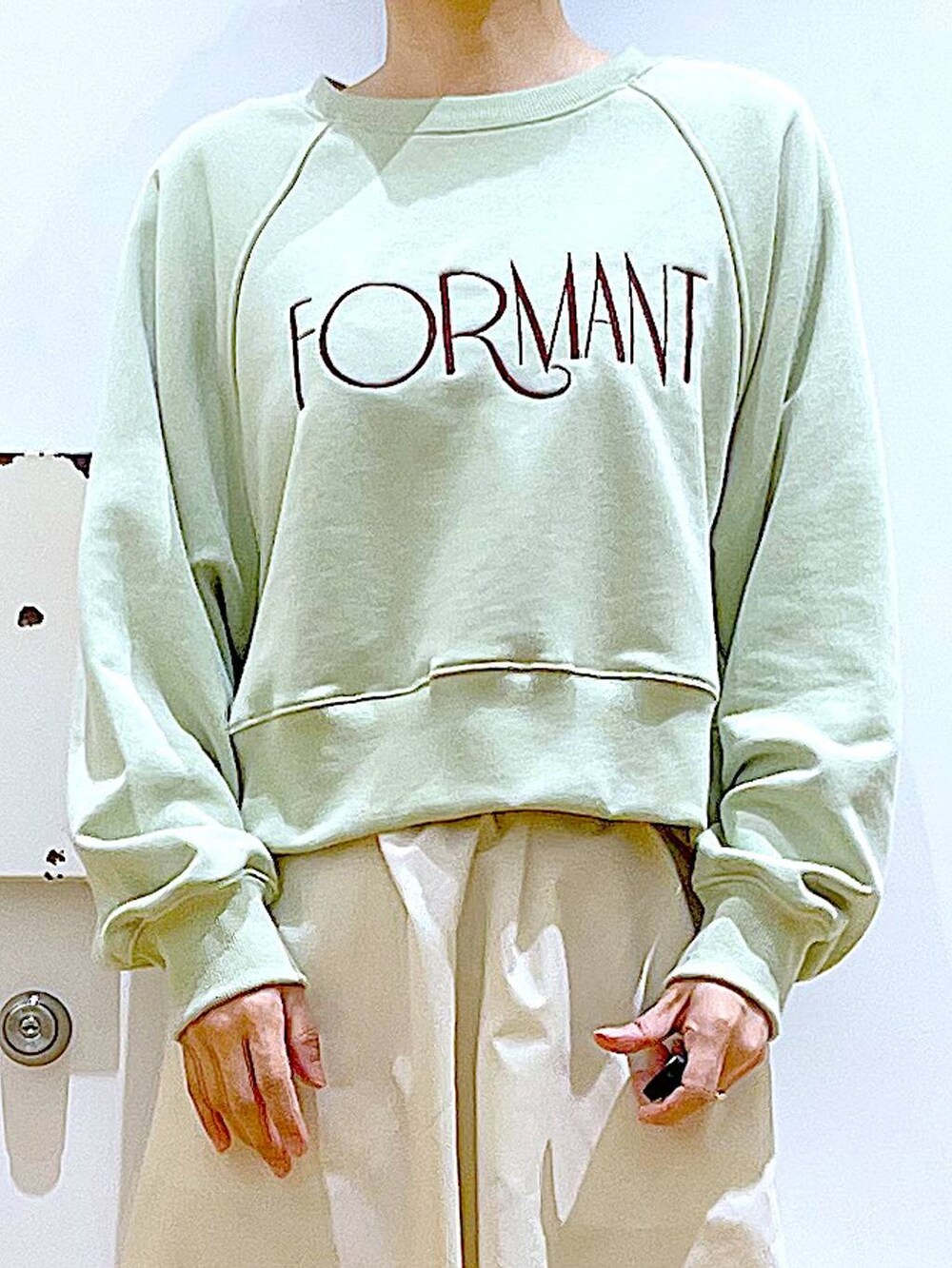 ホワイト系のパンプス、ベージュ系のショルダーバッグ、グリーン系のスウェットを着用したレディースの春コーディネートの7枚目の写真