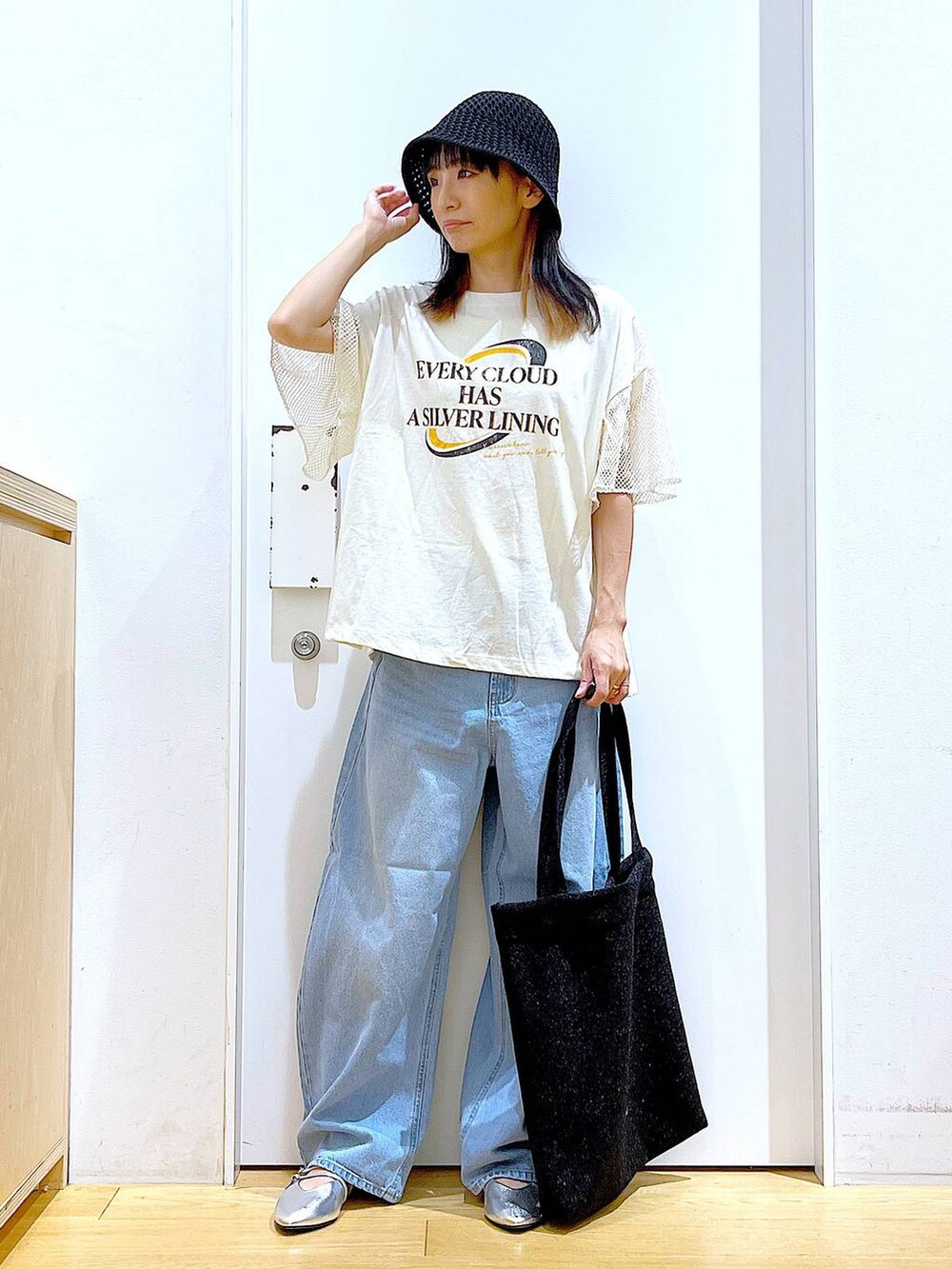 ブラック系のトートバッグ、ブルー系のデニムパンツ、シルバー系のパンプスを着用したレディースの夏コーディネートの2枚目の写真