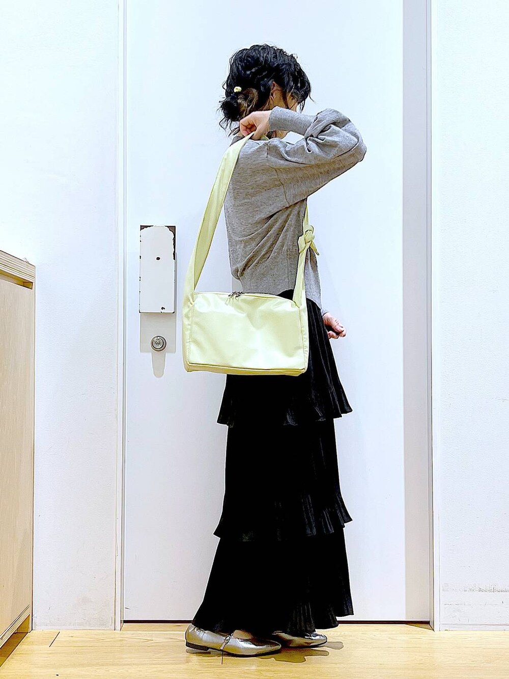 ブラック系のカーディガン/ボレロ、ブラック系のスカート、イエロー系のショルダーバッグを着用したレディースの春コーディネートの4枚目の写真
