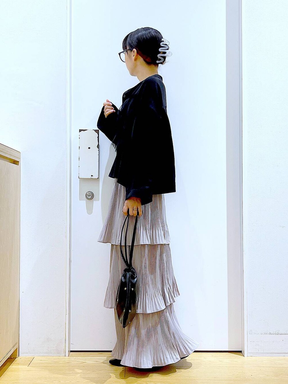 グレー系のスカート、ブラック系のショルダーバッグ、ブラック系のパンプスを着用したレディースの秋コーディネートの3枚目の写真